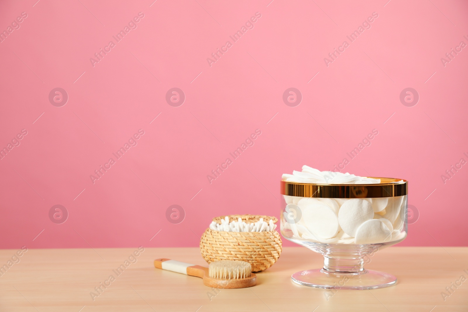 Photo of Jar with cotton pads on wooden table against pink background. Space for text