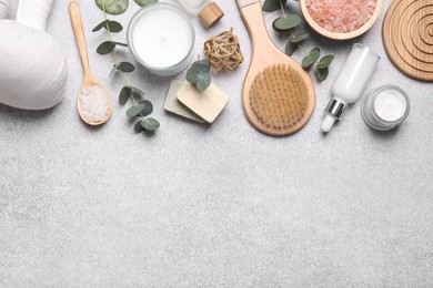 Flat lay composition with herbal massage bags, spa products and eucalyptus branches on light grey table. Space for text