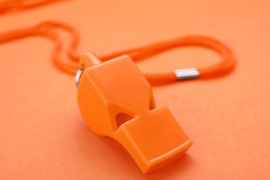 One color whistle with cord on orange background, closeup