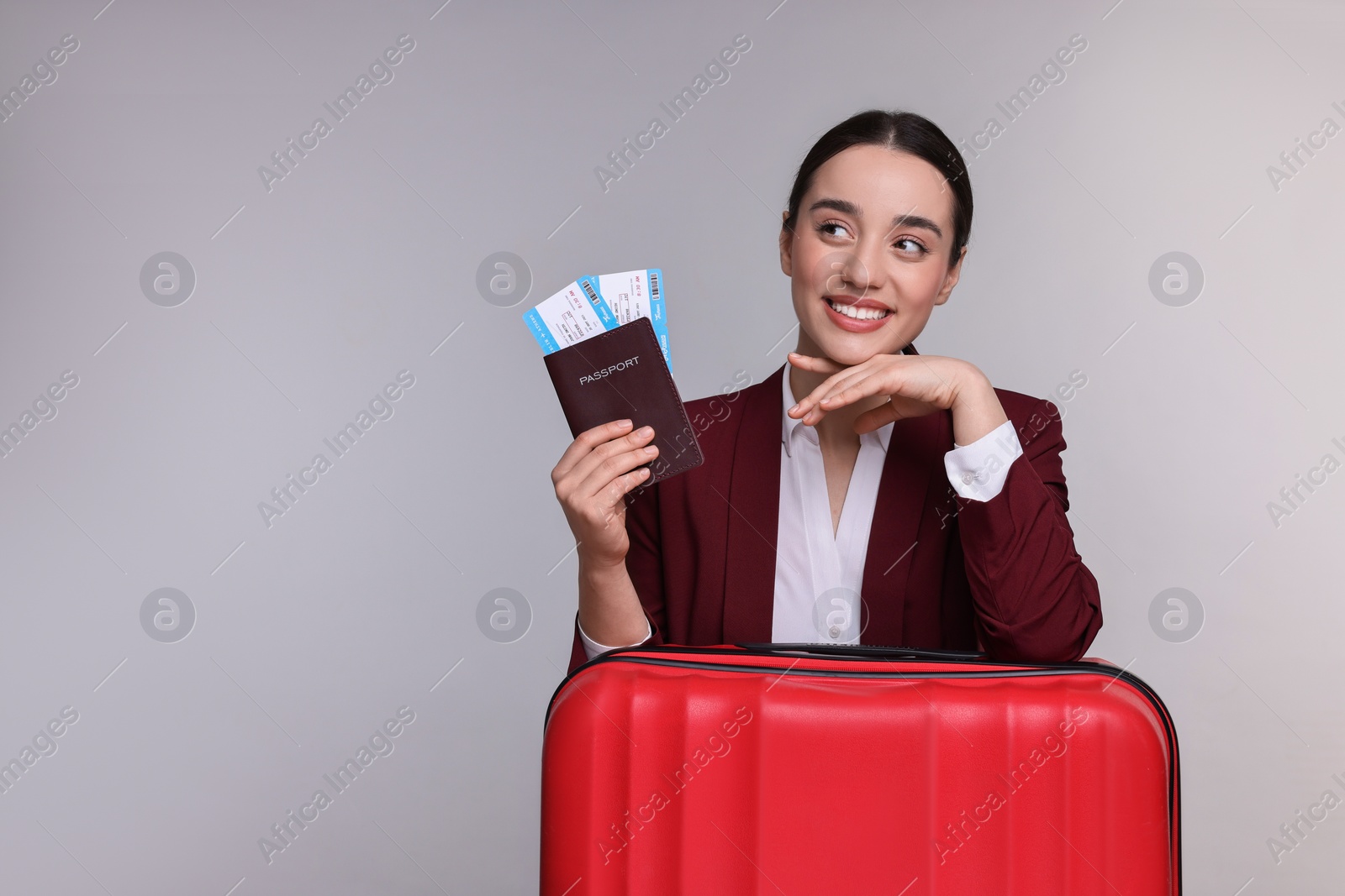 Photo of Happy businesswoman with passport, tickets and suitcase on grey background. Space for text