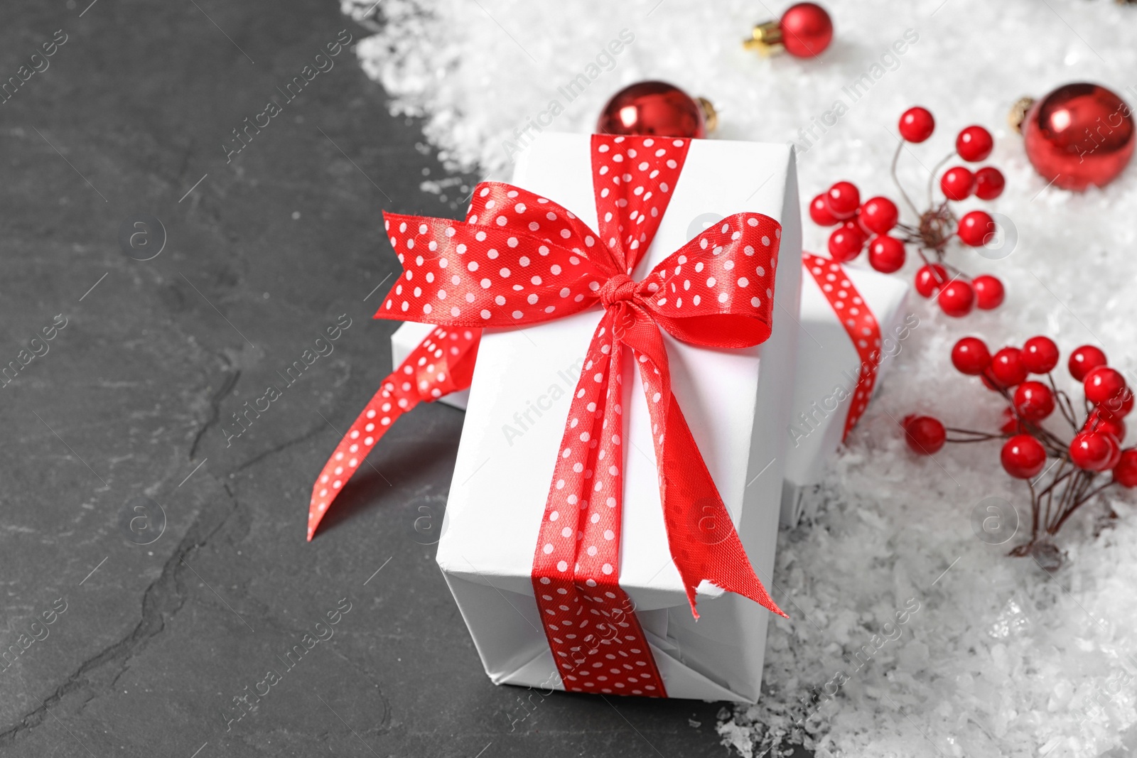 Photo of White Christmas gift box with red bow on grey table