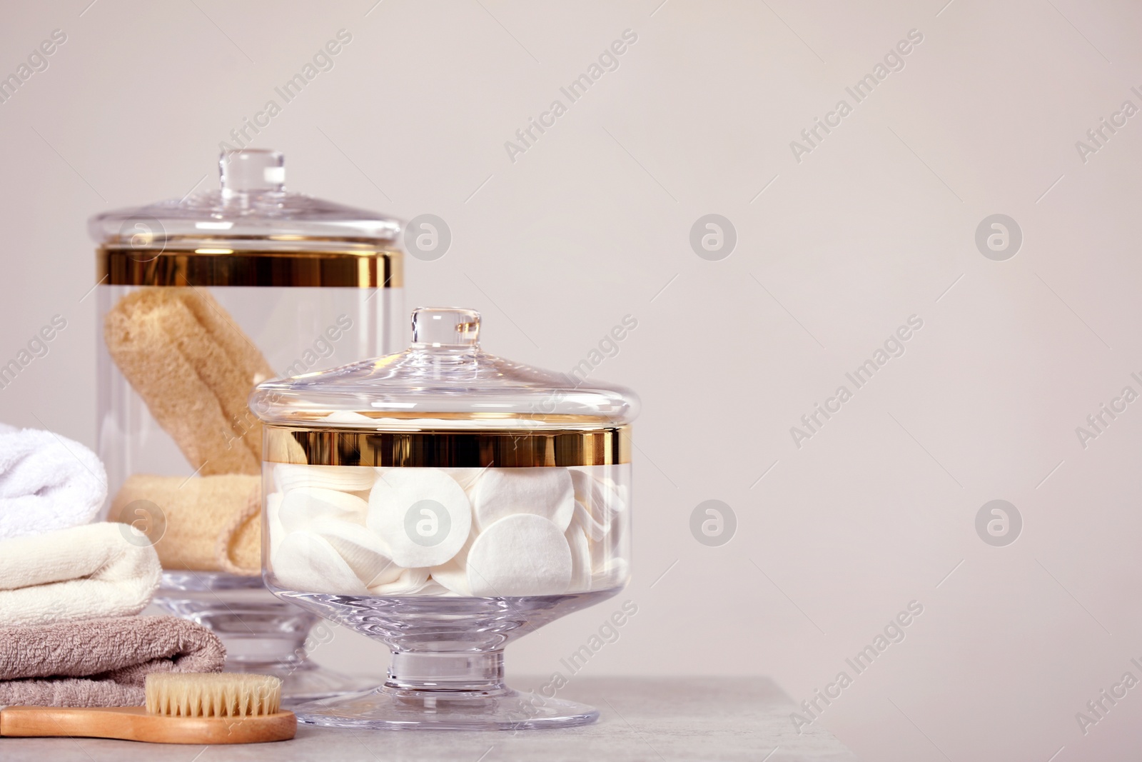 Photo of Composition of glass jar with cotton pads on table near light wall. Space for text