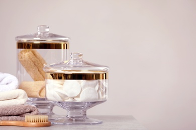 Composition of glass jar with cotton pads on table near light wall. Space for text