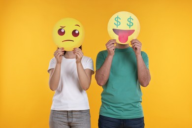 People covering faces with emoticons on yellow background