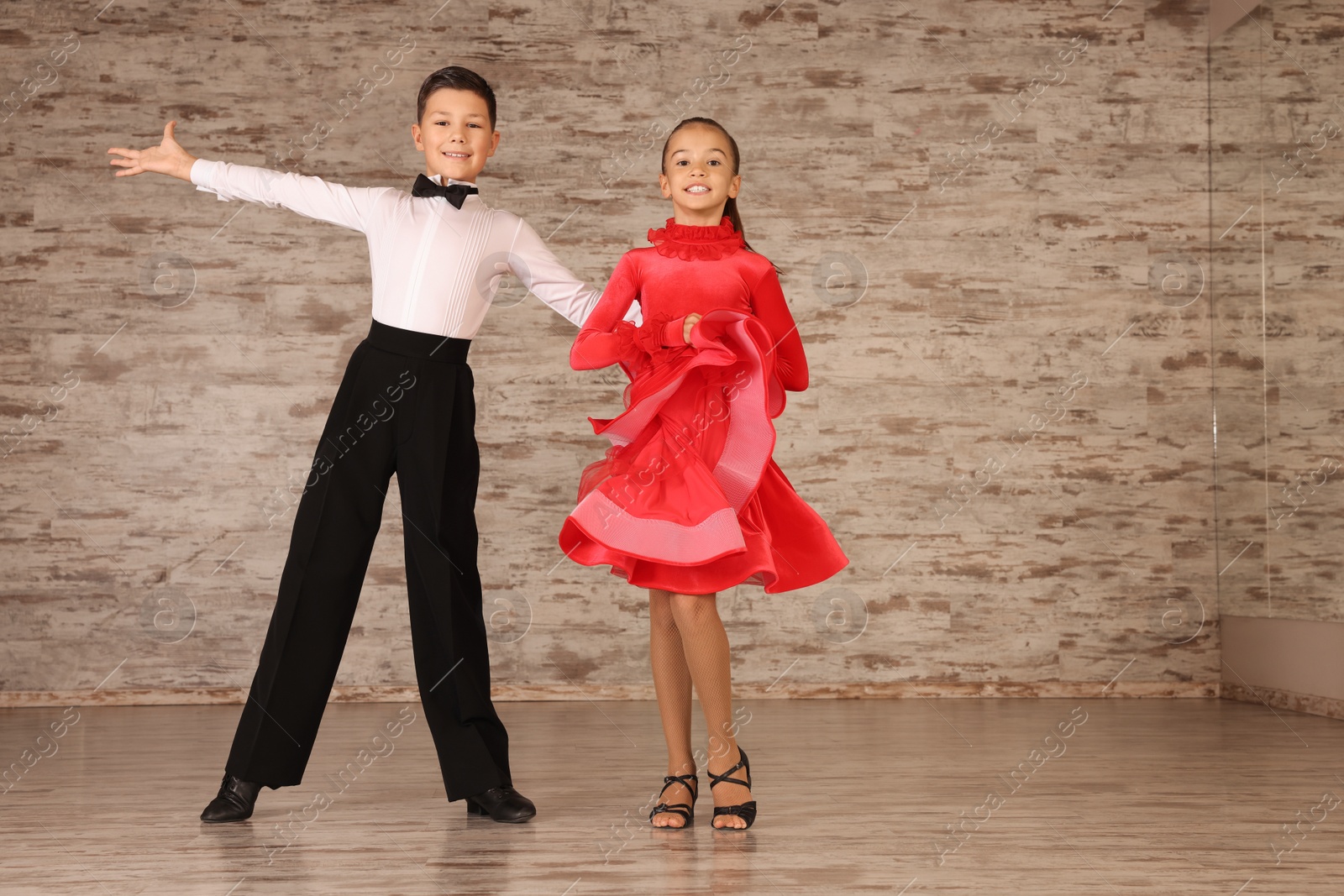 Photo of Beautifully dressed couple of kids dancing together in studio