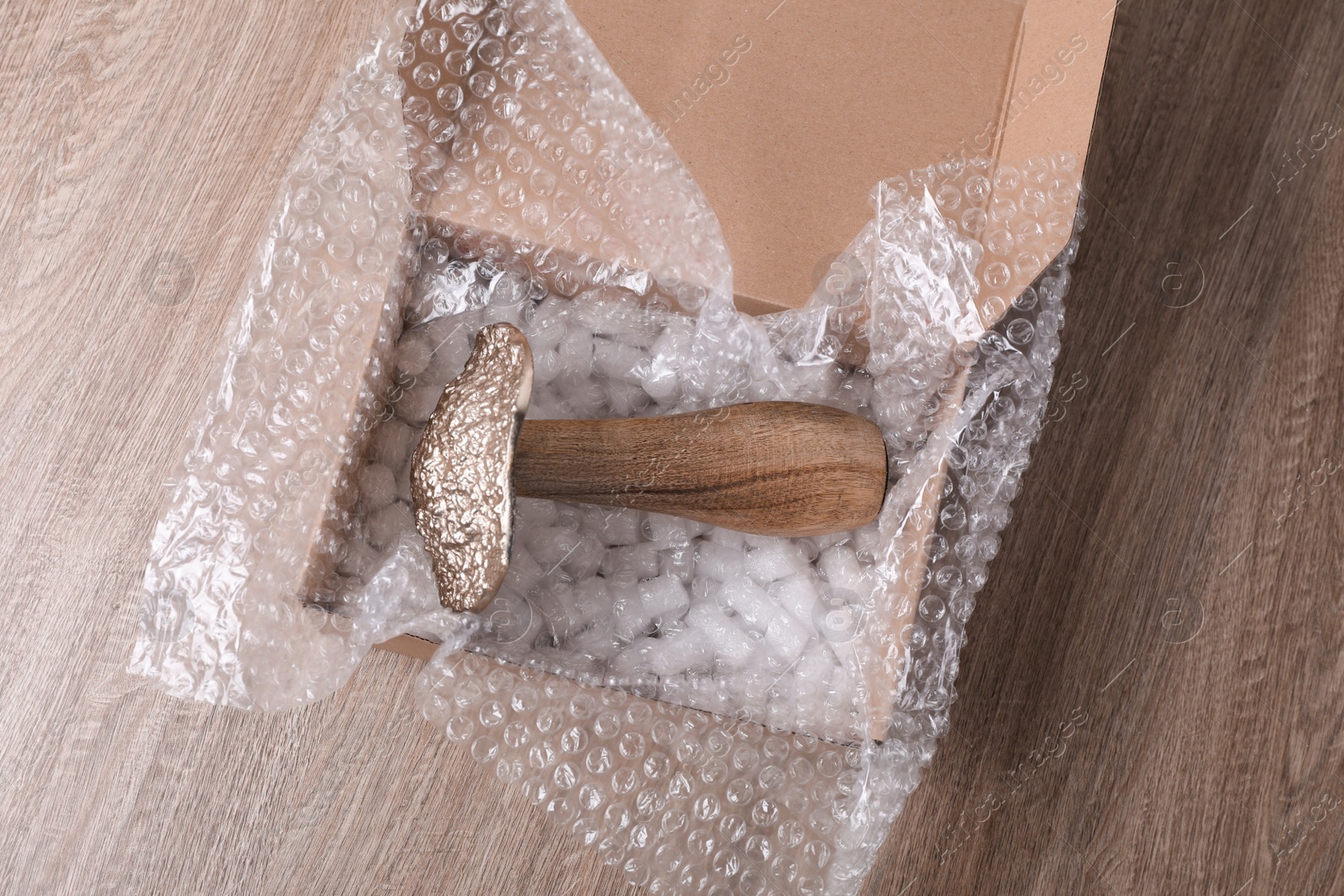 Photo of Decorative mushroom with bubble wrap and packaging foam in cardboard box on wooden table, above view