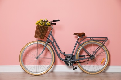 Photo of Retro bicycle with wicker basket near color wall