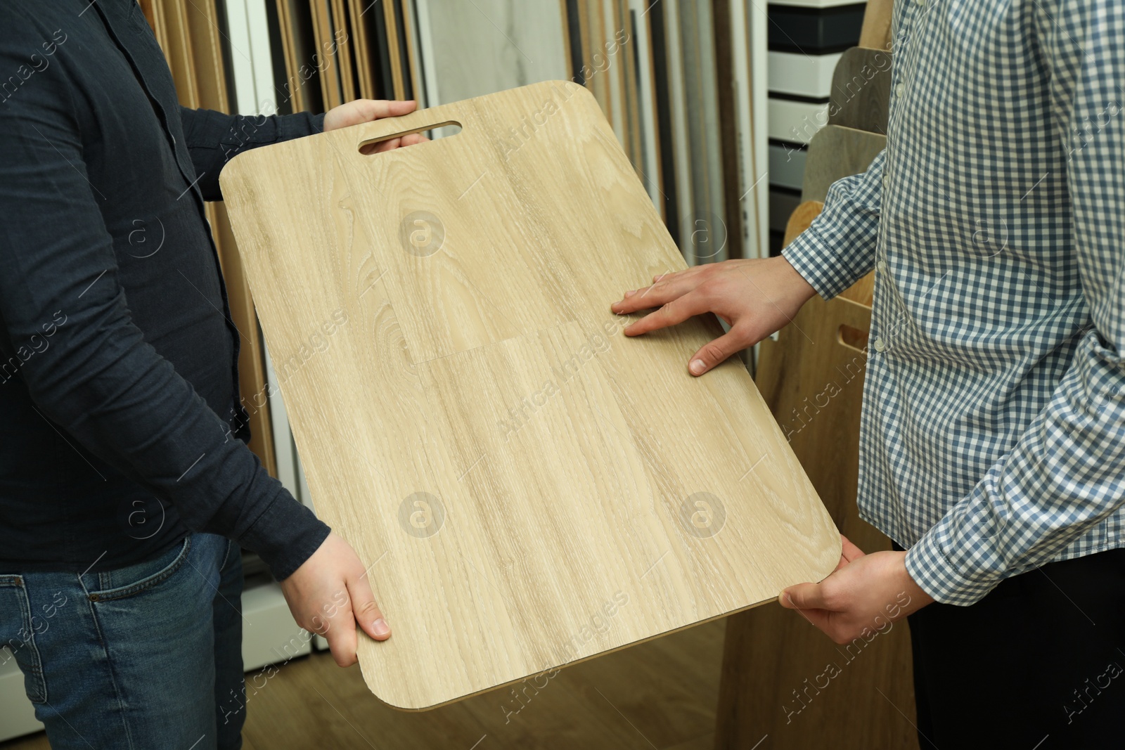 Photo of Men holding sample of wooden flooring in shop, closeup