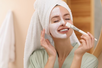 Photo of Woman applying face mask indoors. Spa treatments