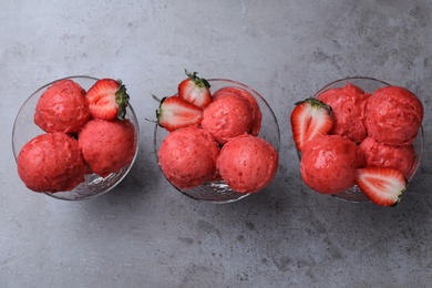 Photo of Delicious strawberry ice cream in dessert bowls on grey table, flat lay