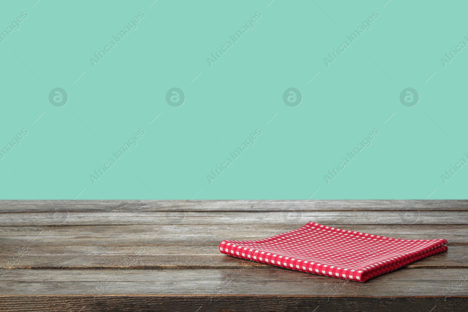 Image of Folded kitchen towel on wooden table against mint background. Space for design