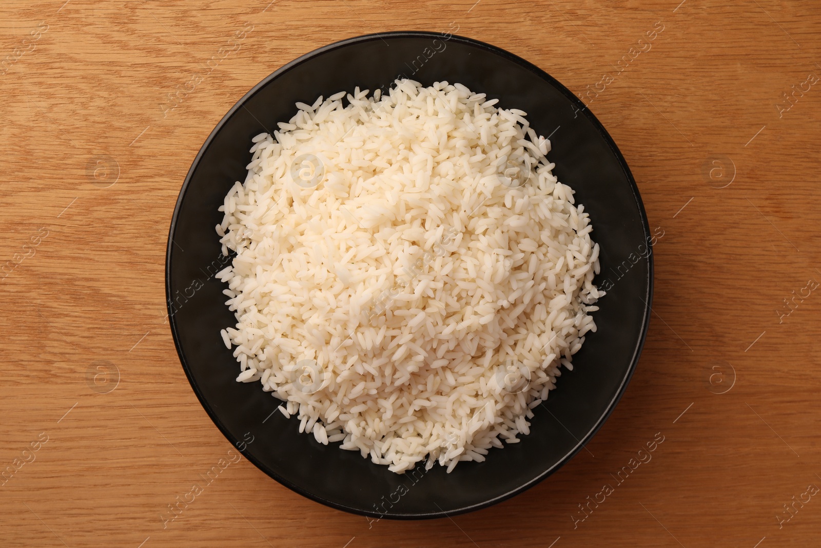 Photo of Plate with delicious rice on wooden table, top view