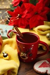Photo of Composition with cup of hot drink and yellow sweater on wooden table