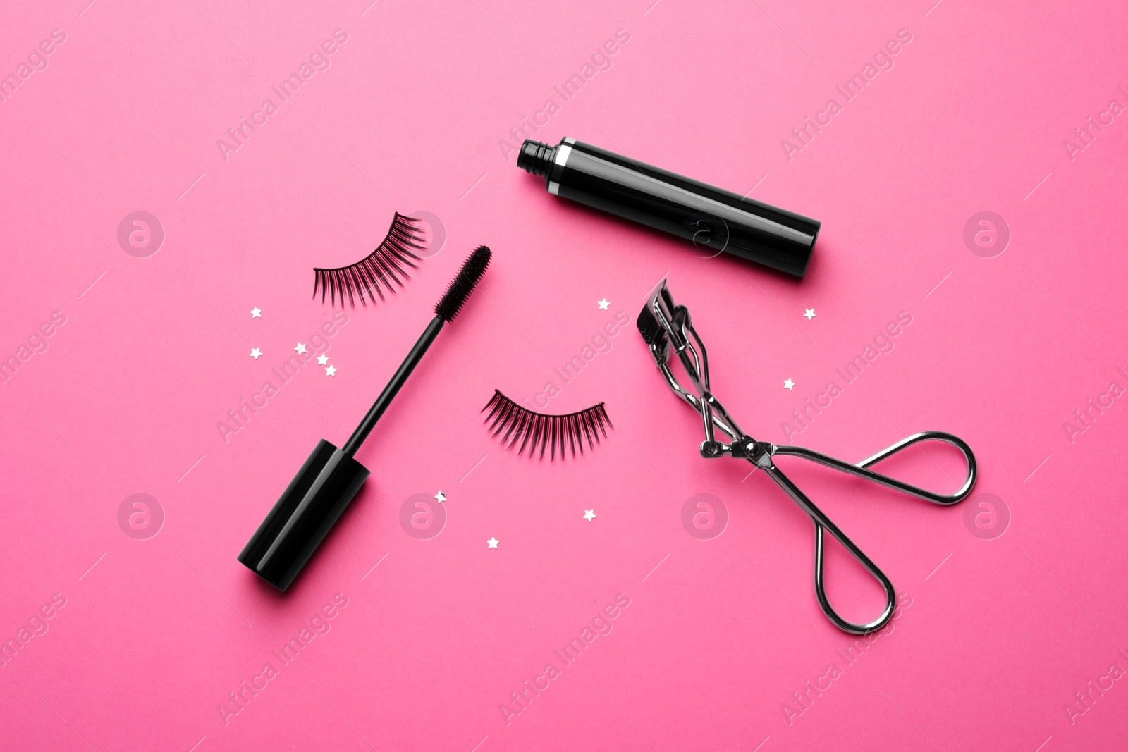 Photo of False eyelashes, curler and mascara on pink background, flat lay