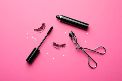 False eyelashes, curler and mascara on pink background, flat lay