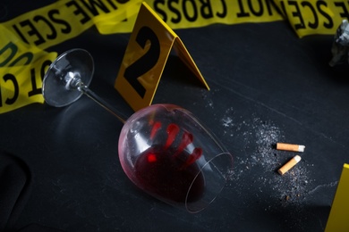 Photo of Wine glass with fingerprints and stubs on black slate table. Crime scene