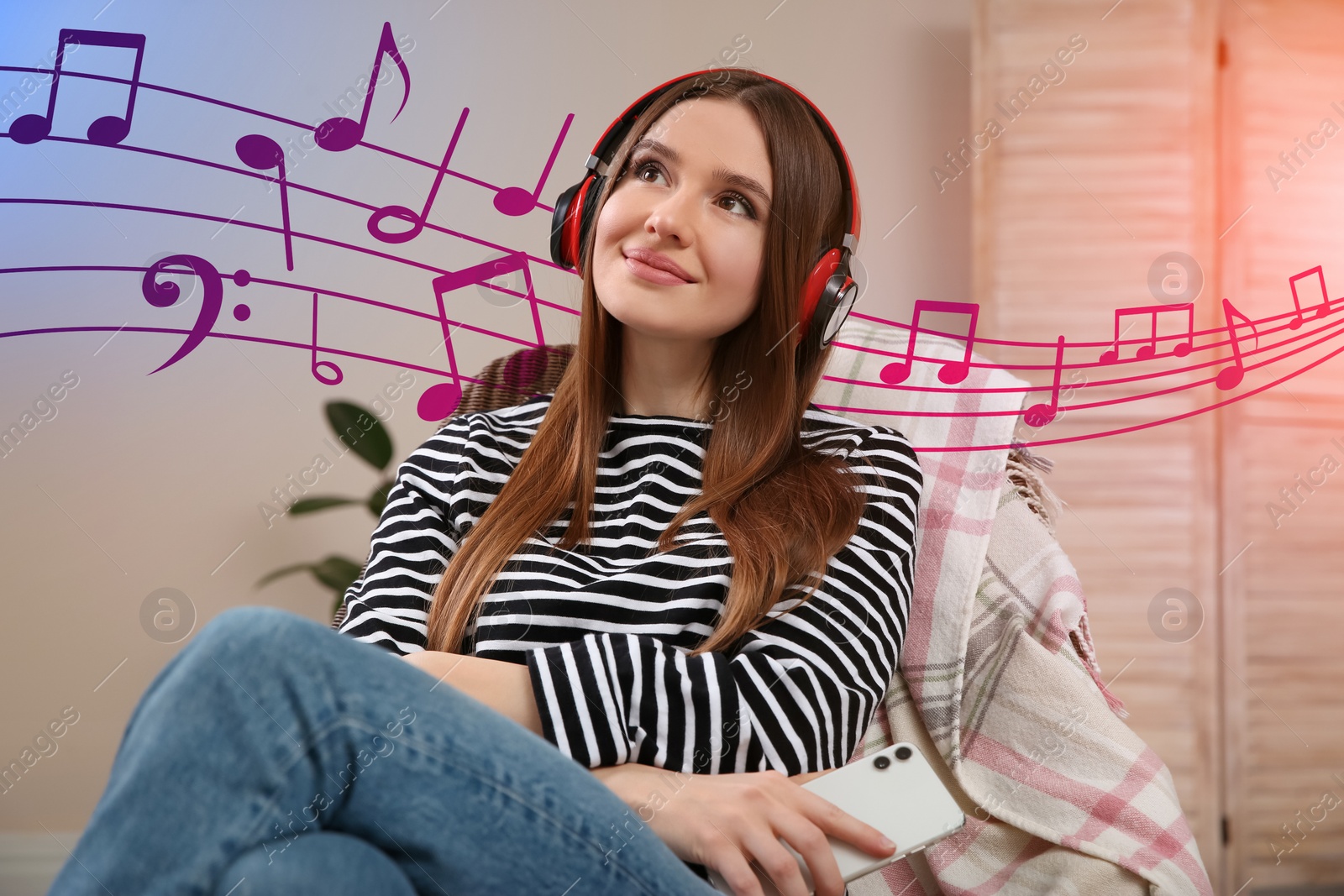 Image of Woman listening to music through headphones in chair at home