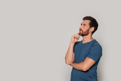 Photo of Portrait of pensive bearded man on grey background. Space for text