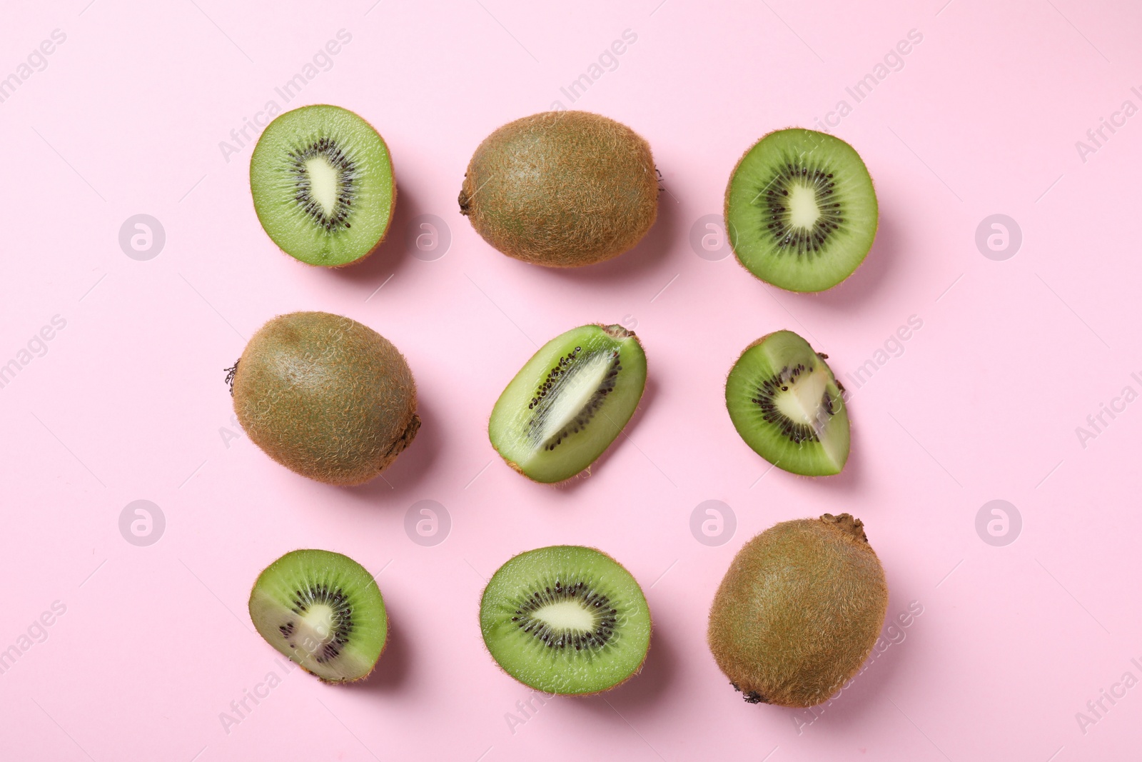 Photo of Top view of cut and whole fresh kiwis on pink background
