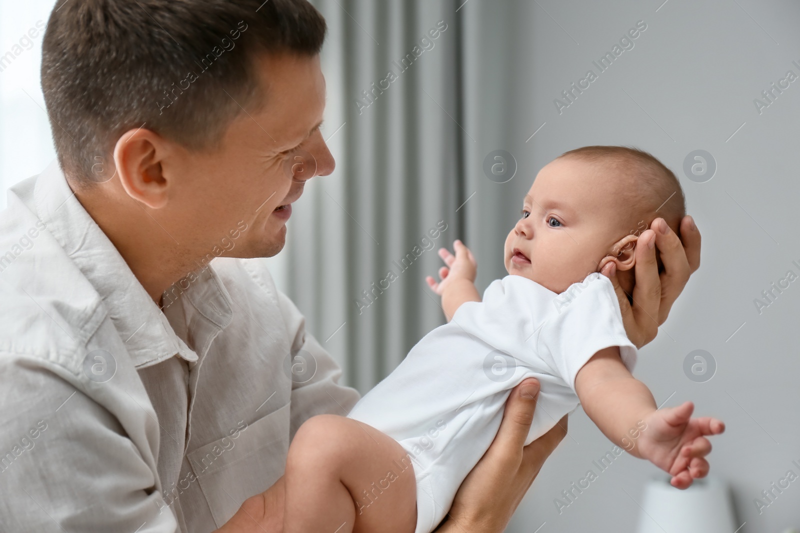 Photo of Happy father holding his cute baby at home