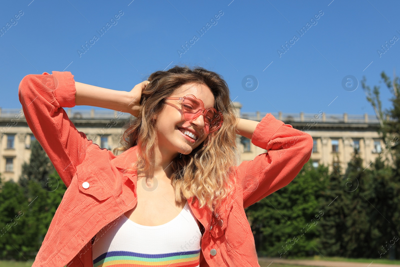 Photo of Portrait of happy young woman with heart shaped glasses in city on sunny day