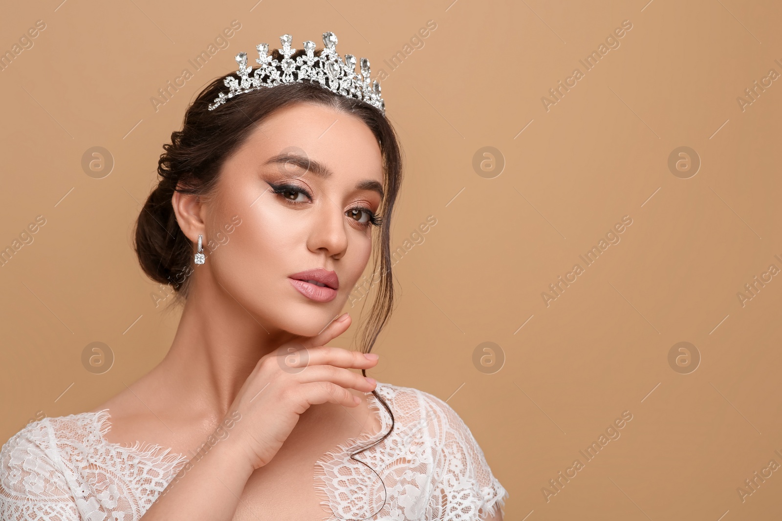Photo of Beautiful young woman wearing luxurious tiara on beige background, space for text