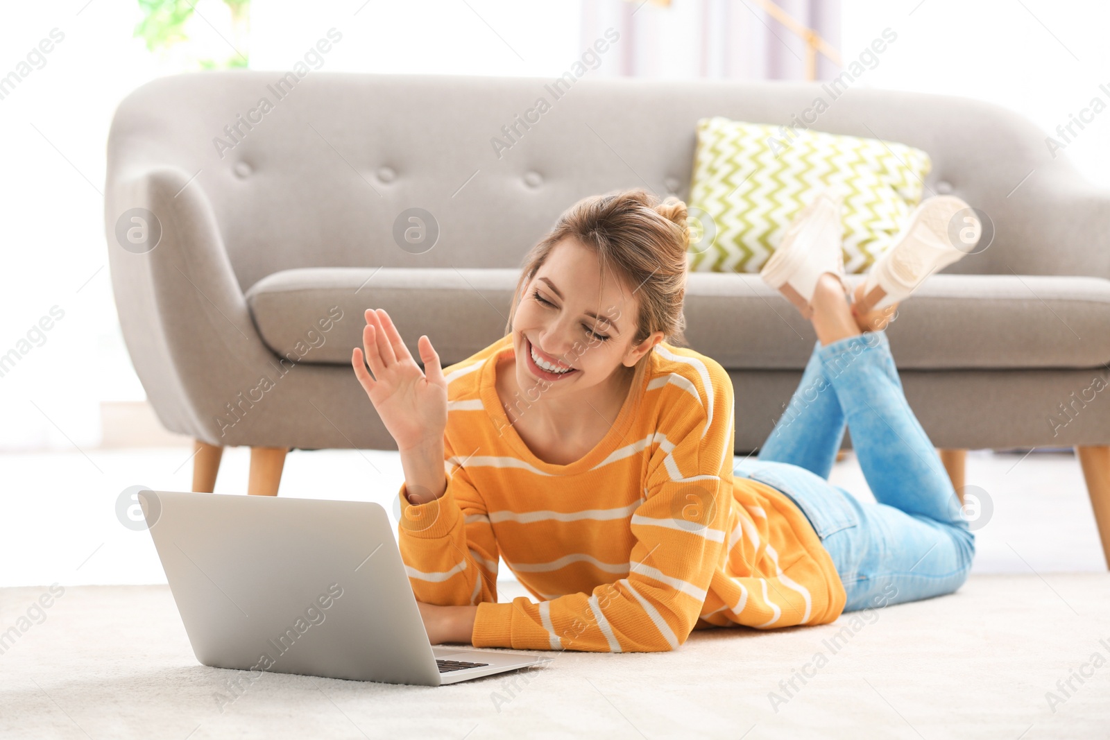 Photo of Woman using laptop for video chat in living room