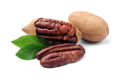 Photo of Many tasty pecan nuts with green leaves isolated on white