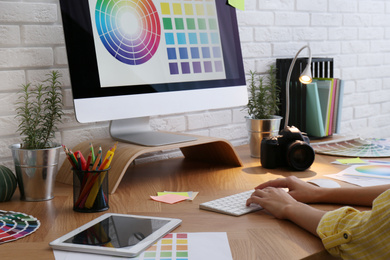 Photo of Designer working with computer at wooden table, closeup