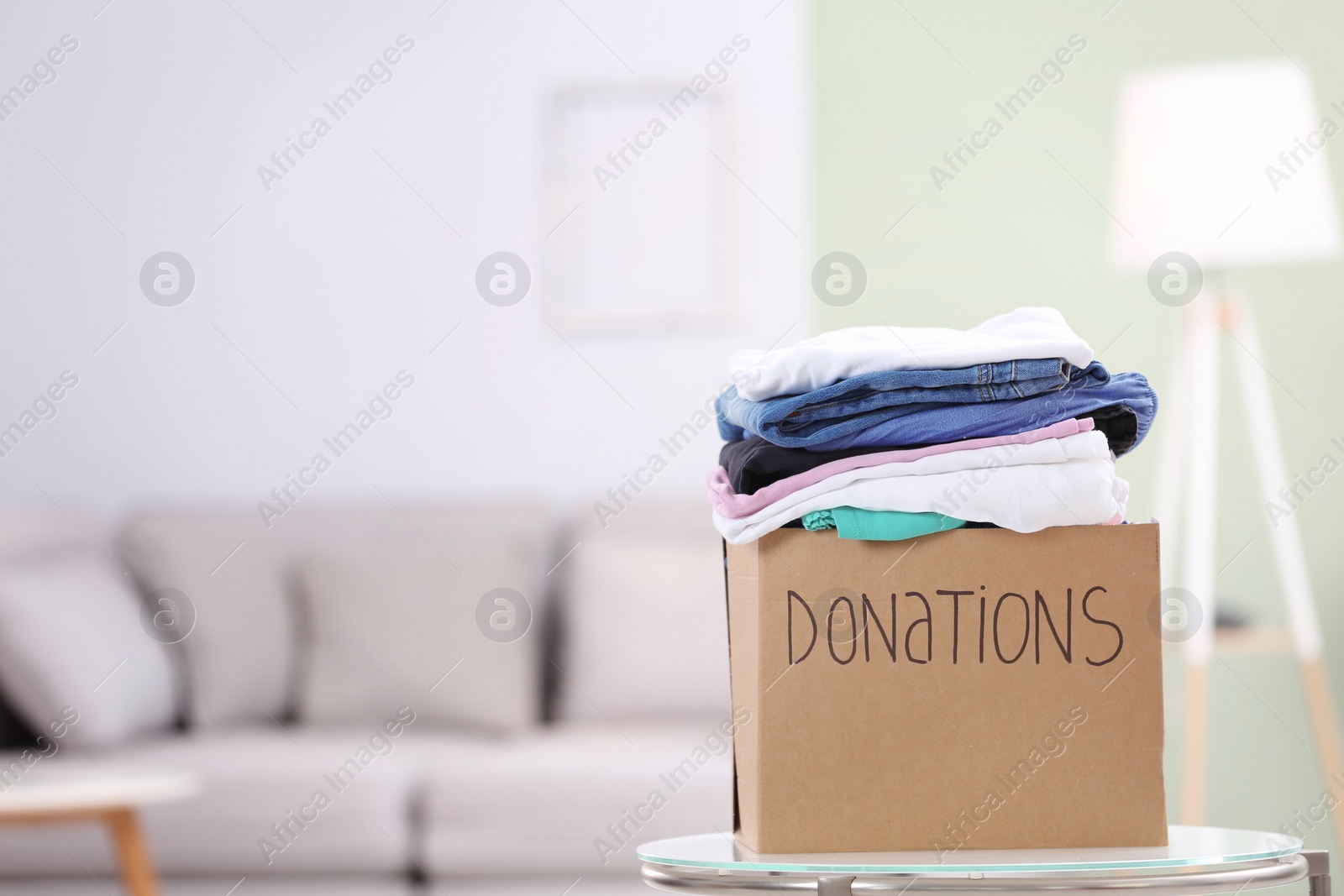 Photo of Donation box with clothes on table indoors