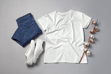 Photo of Stylish t-shirt, jeans and sneakers on light grey background, flat lay
