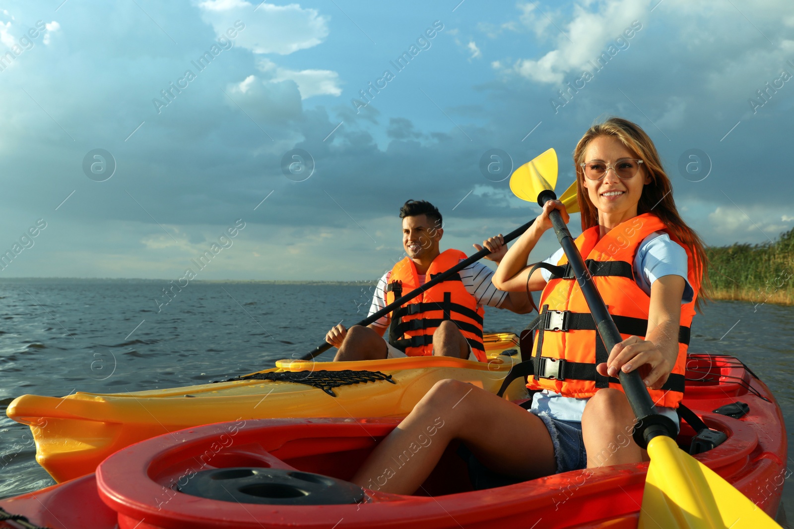 Photo of Couple in life jackets kayaking on river. Summer activity