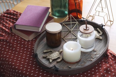 Wooden tray with decorations and books on table