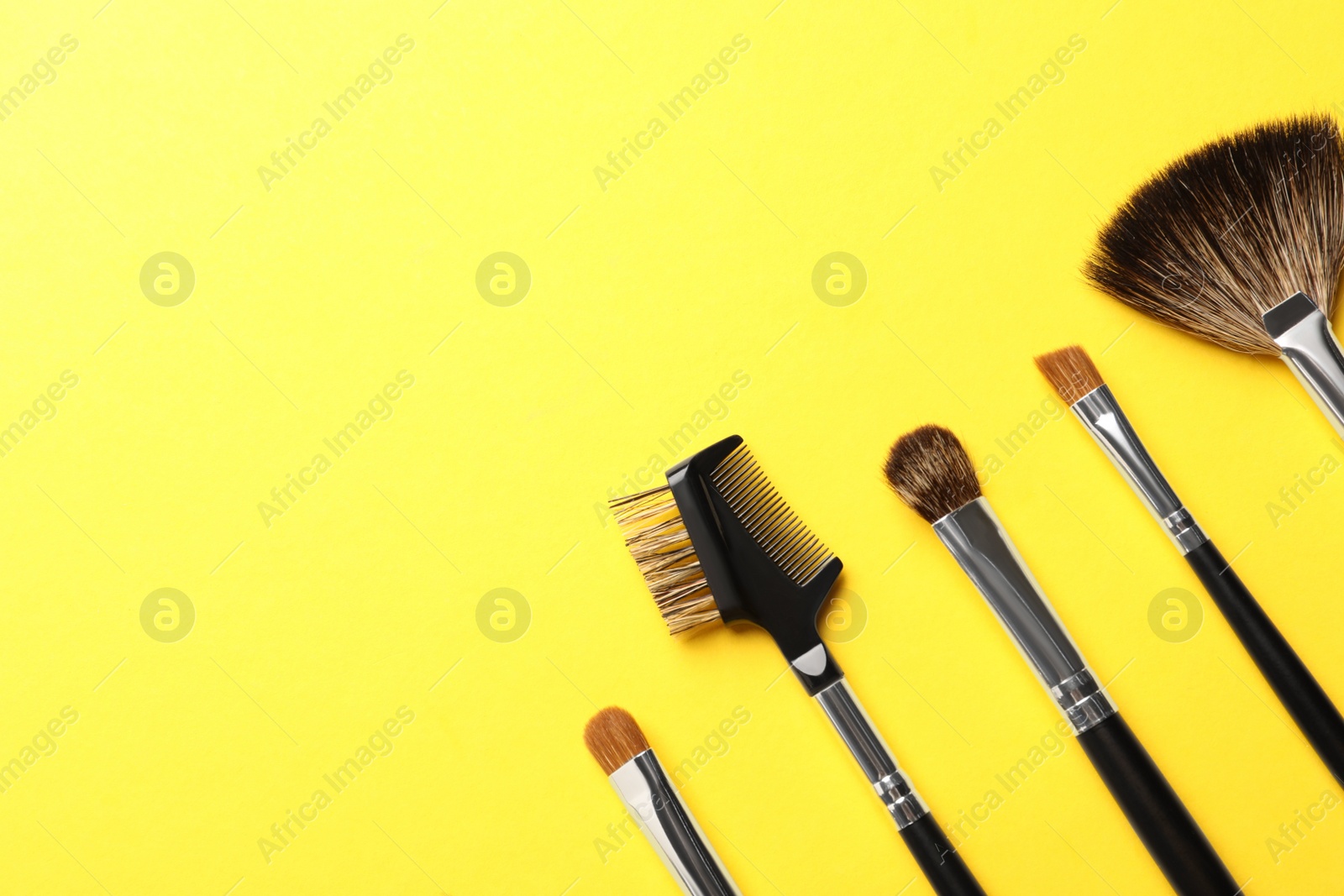 Photo of Set of makeup brushes on yellow background, flat lay. Space for text