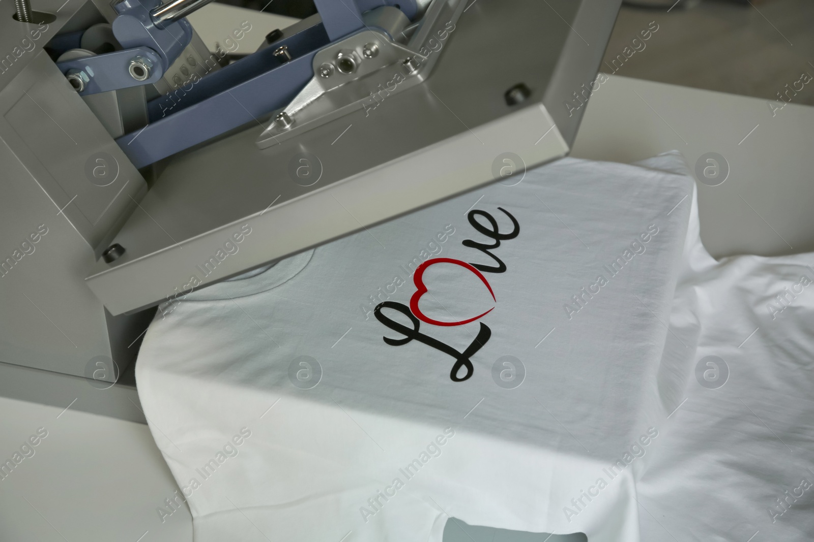 Photo of Printing logo. Heat press with t-shirt on white table