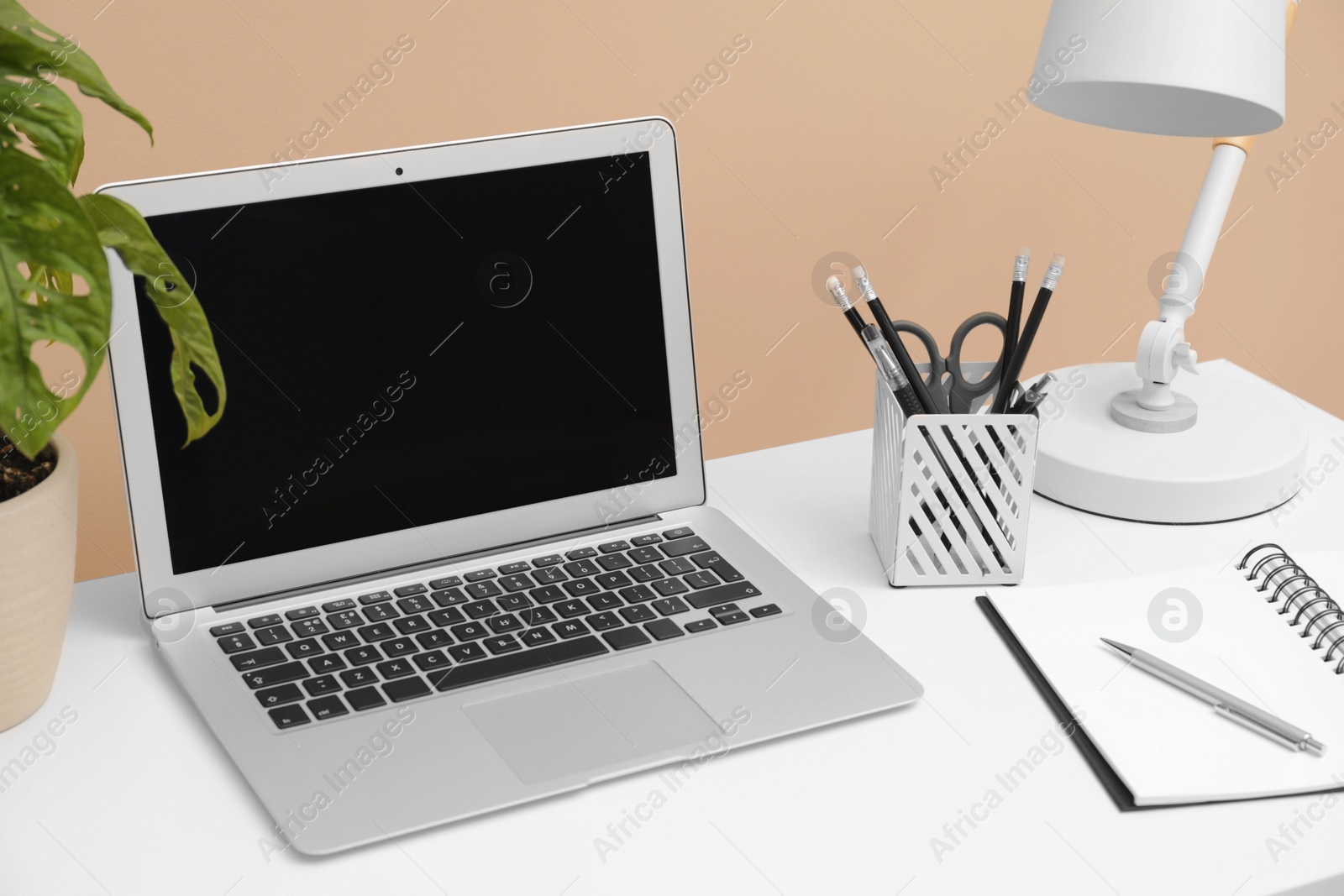 Photo of Cozy workplace with laptop and stationery on desk. Home office