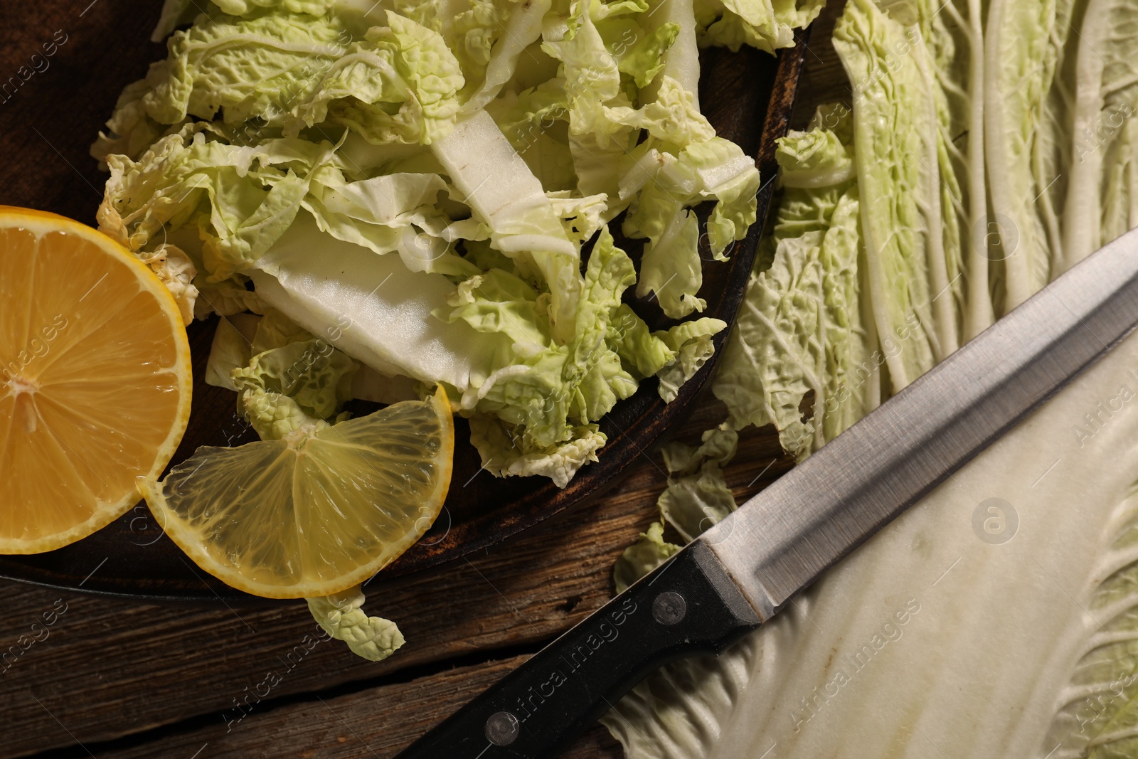 Photo of Fresh Chinese cabbage, lemon and knife on wooden table, flat lay