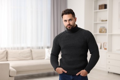 Handsome man in stylish sweater at home, space for text