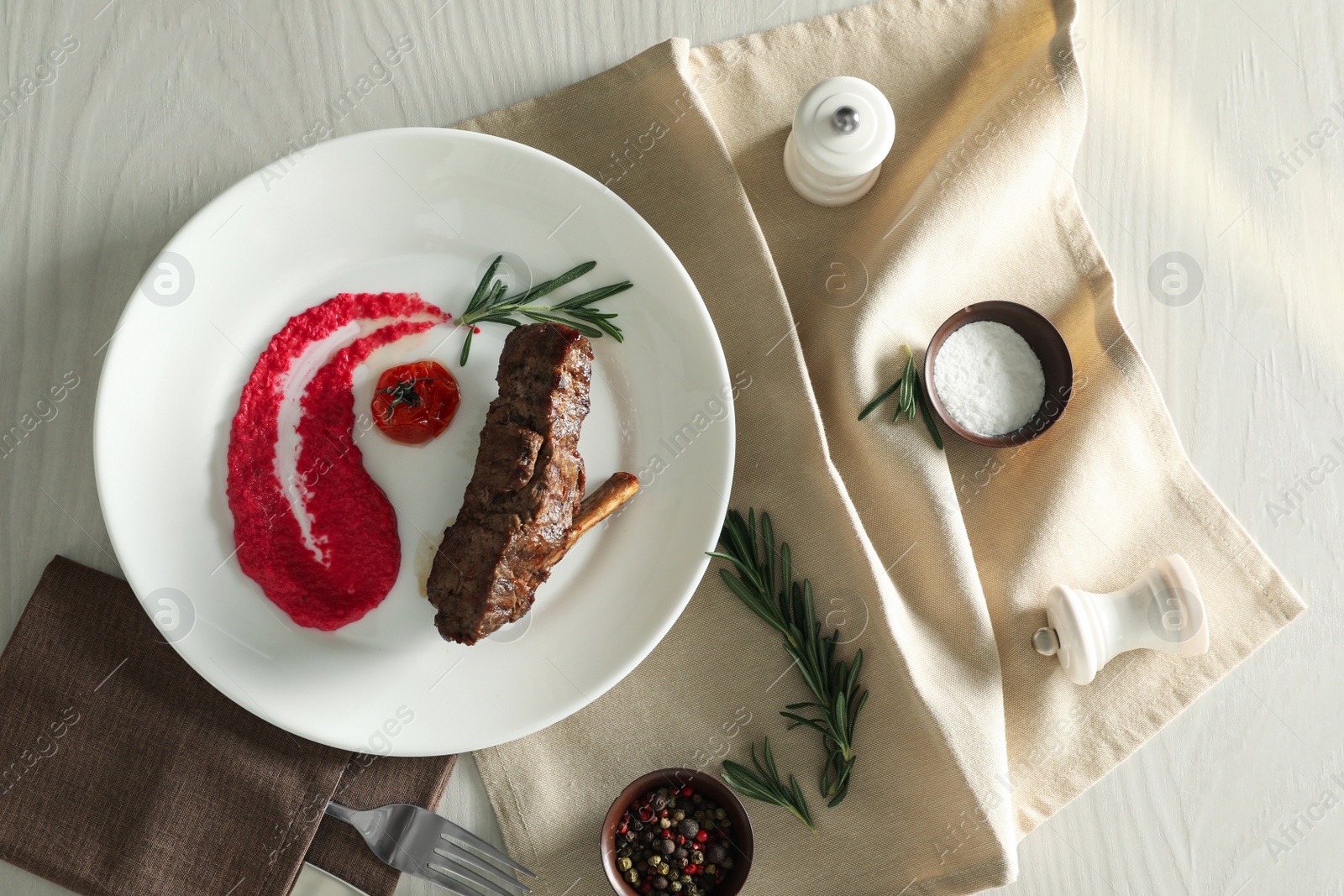 Photo of Delicious roasted rib served on white wooden table, flat lay