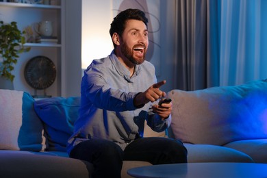 Excited man watching TV on sofa at home