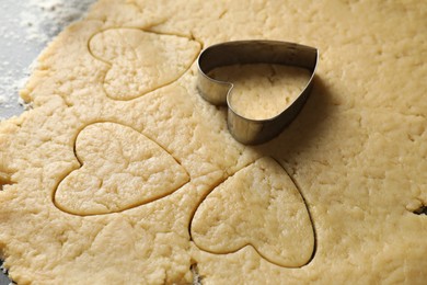 Photo of Making shortcrust pastry. Raw dough and cookie cutter on table, closeup