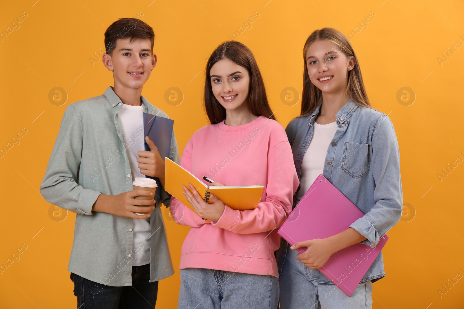 Photo of Group of teenage students with stationery on yellow background