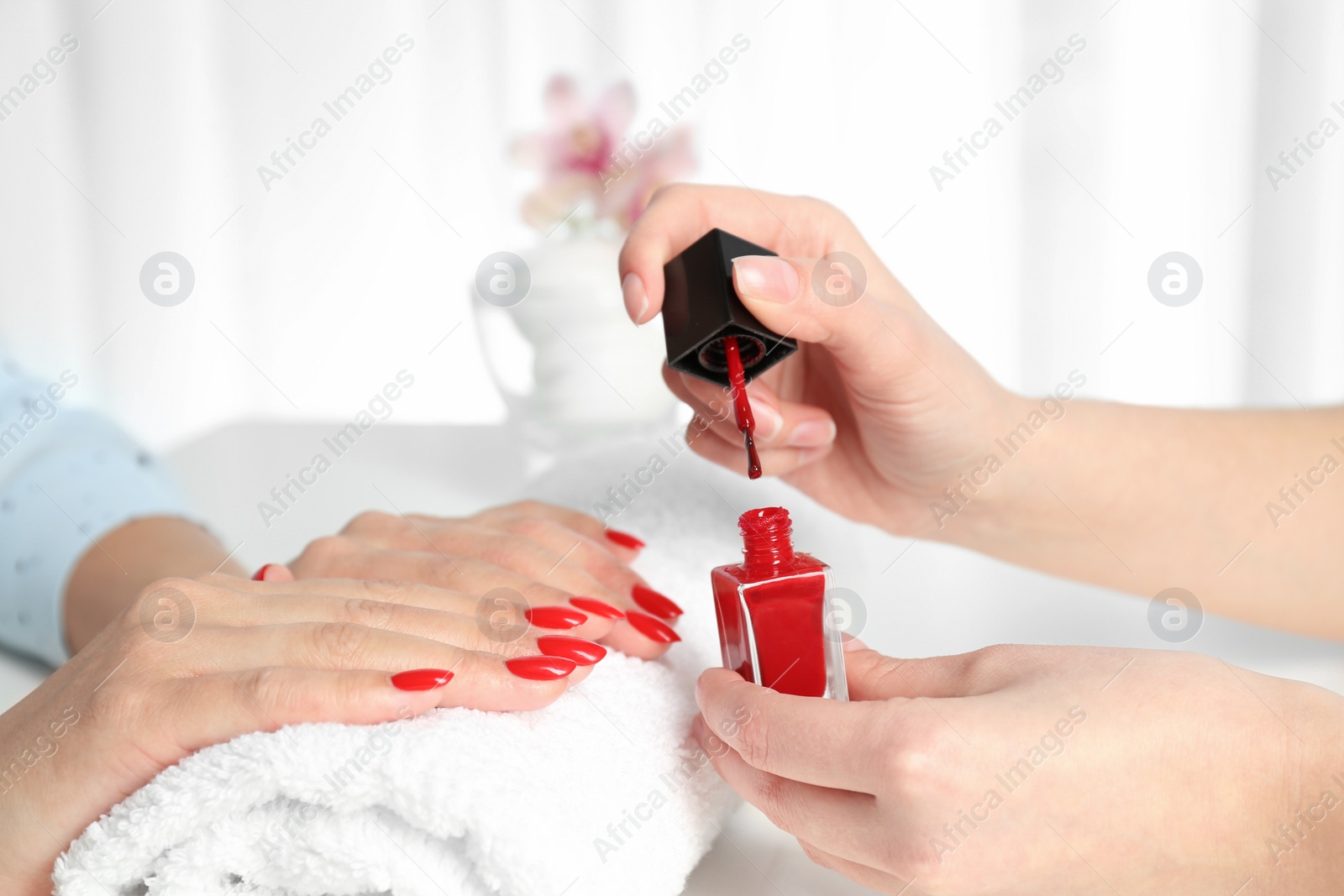 Photo of Manicurist painting client's nails with bright polish in salon, closeup