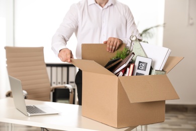 Photo of Young man with box of stuff in office, closeup