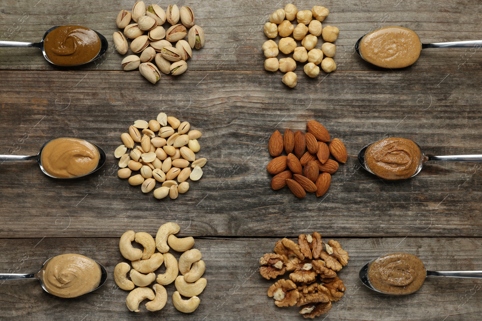 Photo of Tasty nut butters in spoons and raw nuts on wooden table, flat lay