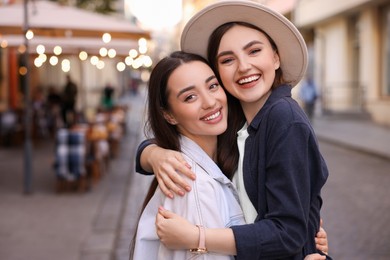 Photo of Portrait of happy friends hugging on city street