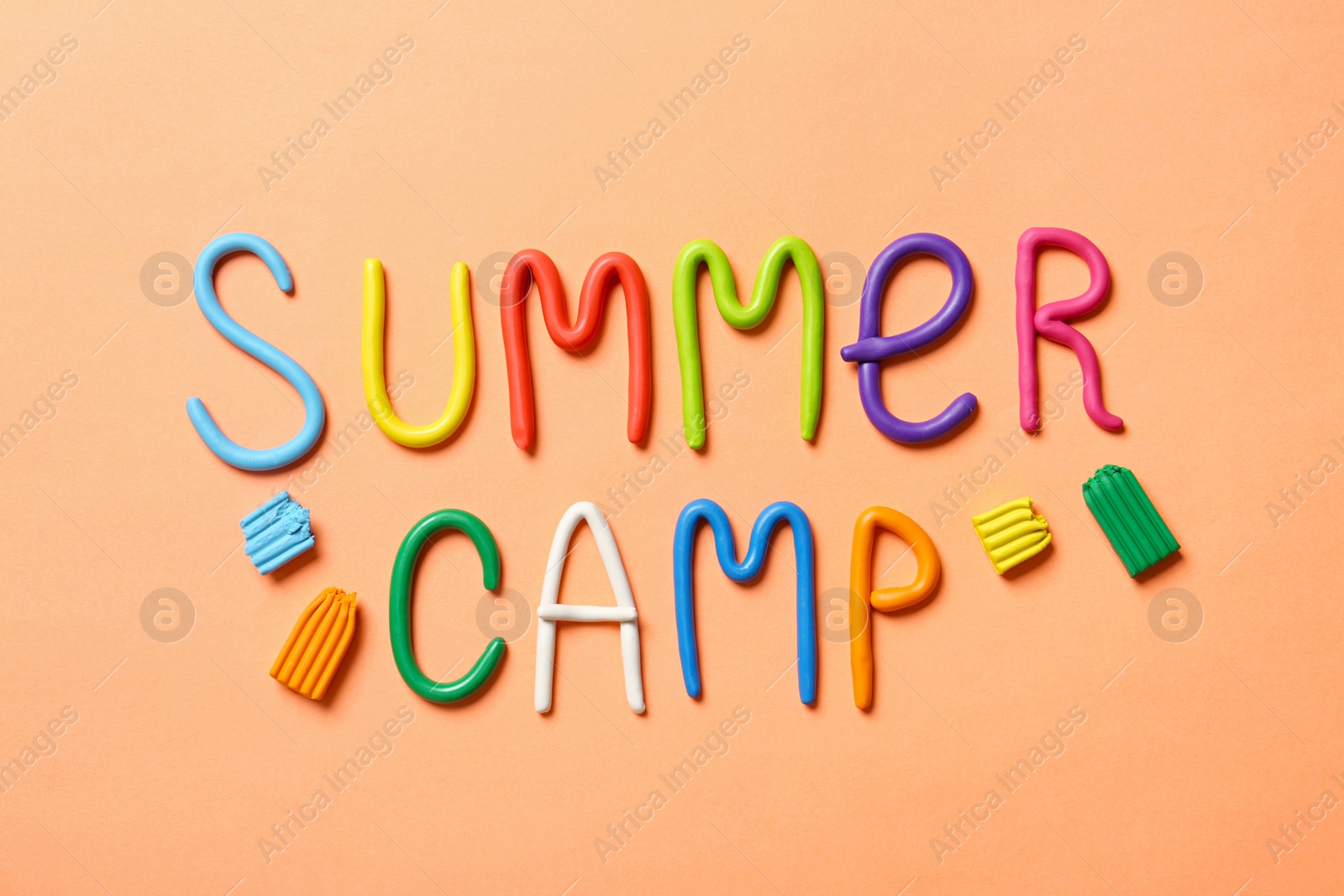 Photo of Text SUMMER CAMP made of modelling clay on color background, flat lay