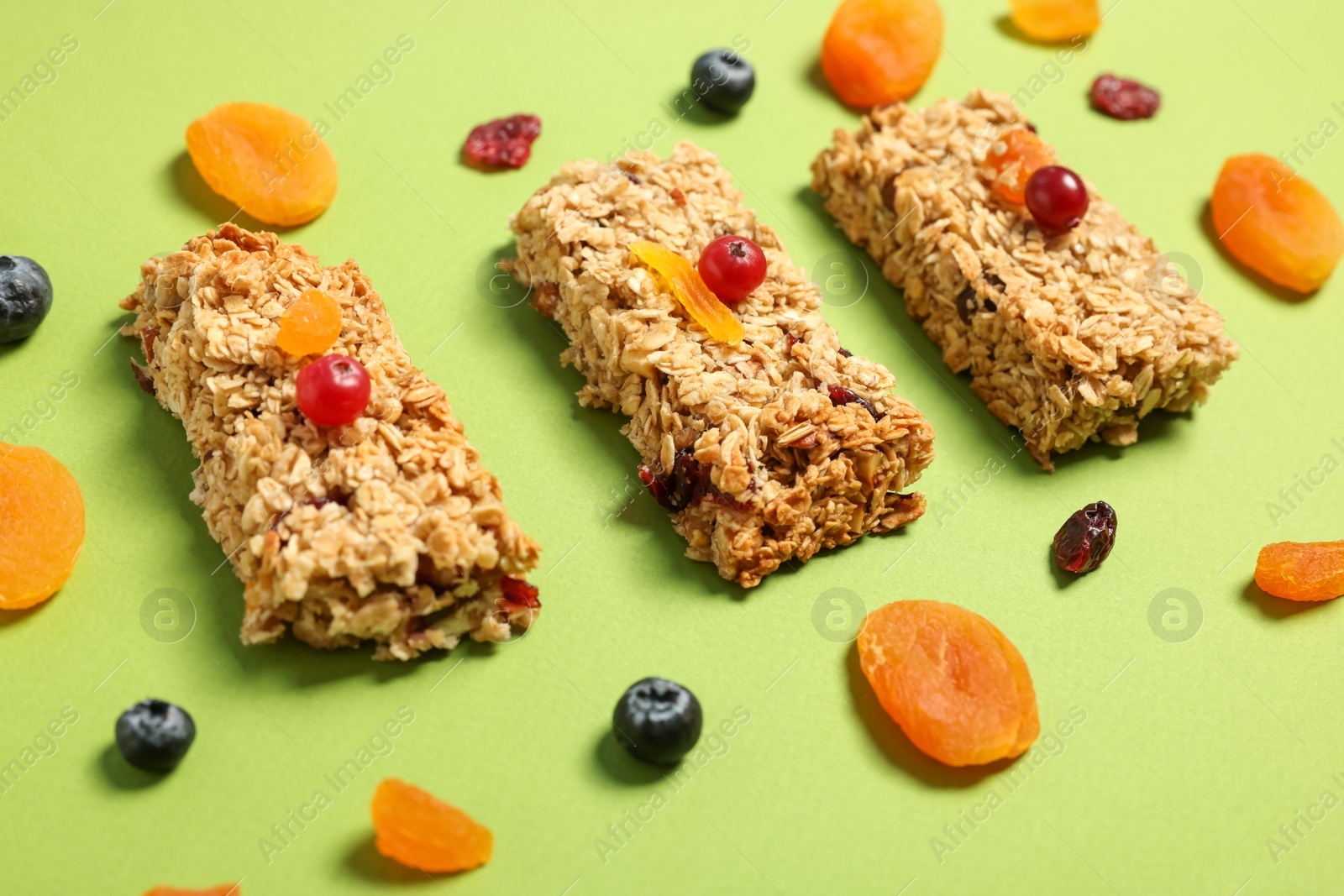 Photo of Tasty granola bars and ingredients on green table