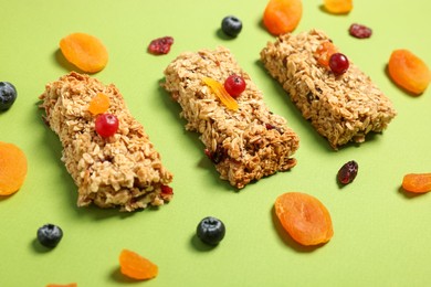 Photo of Tasty granola bars and ingredients on green table