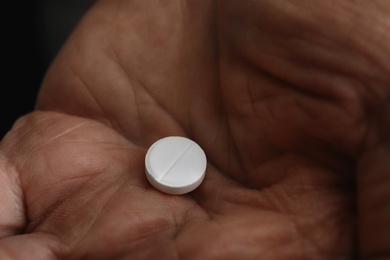 Senior man holding pill in his hand, closeup